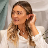 Woman adjusting an earring with a neutral background
